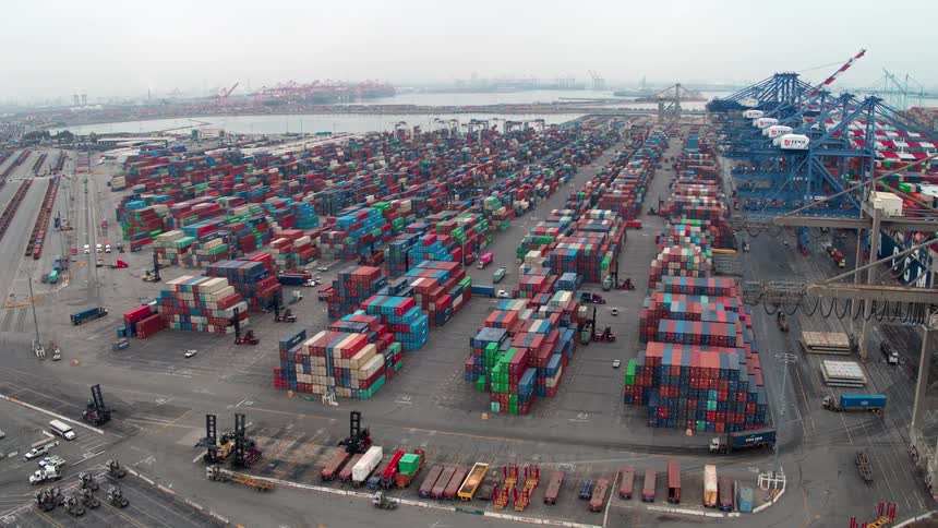 A seaport stacked with containers with more trucks driving in containers at midday in  Los Angeles