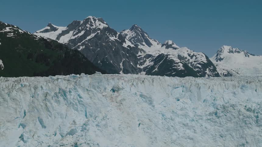 A massive glacier spans the foreground with snowy peaks behind