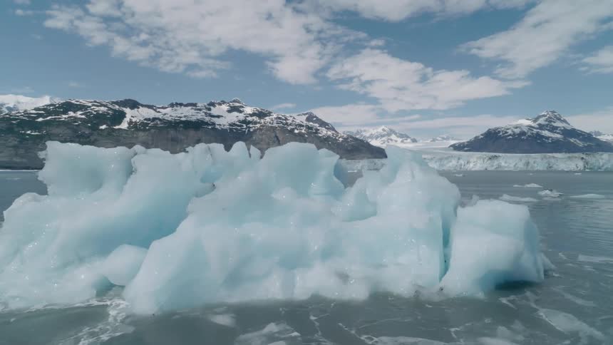 Iceberg in a frozen sea with mountains around it