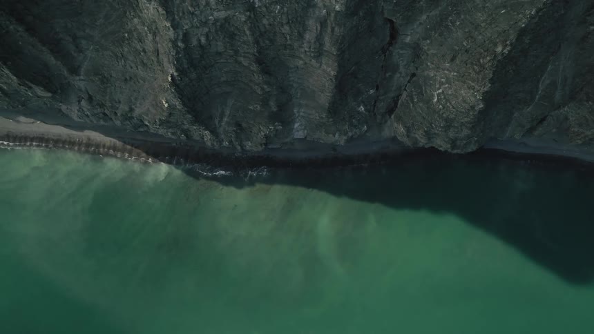 Aerial view of a green beach on the edge of towering mountains