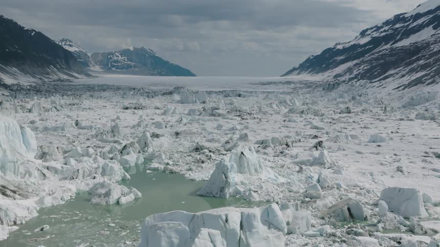 The water is covered with ice by the mountains