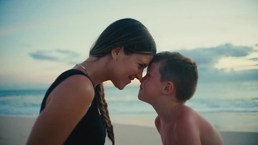 Mother and son touching foreheads in a loving gesture while at the beach