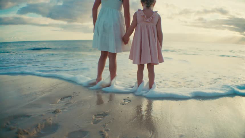 Two girls hold hands and walk into the water