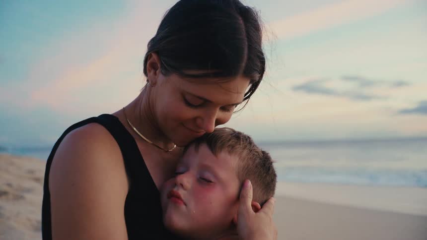 Mother hugging her son on a beach