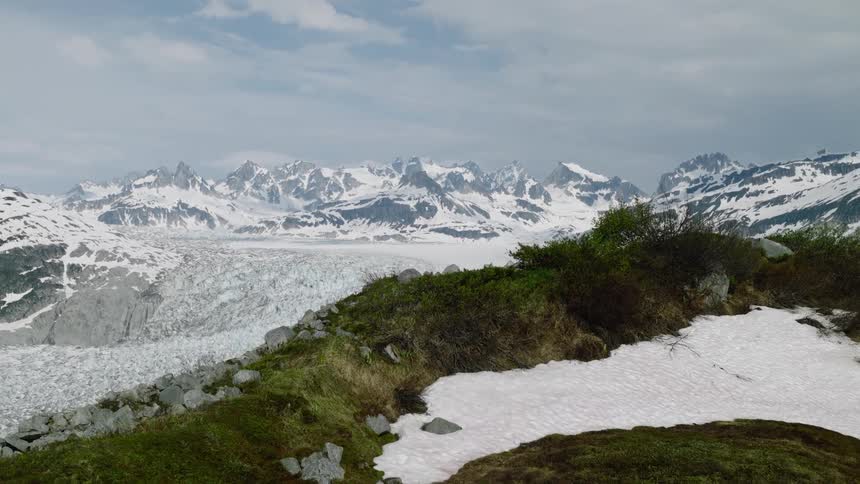 A vast glacier winds through a dramatic snowcovered mountain range