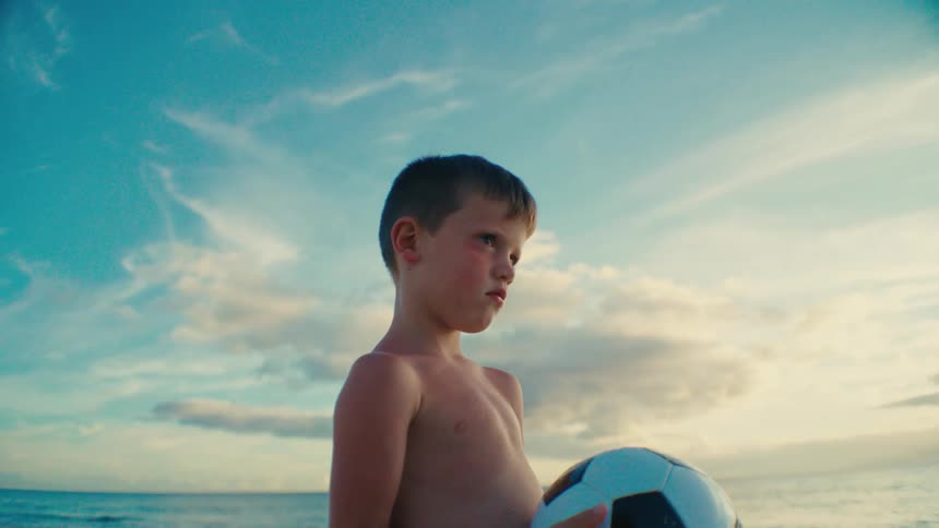 Boy on a beach holding a ball