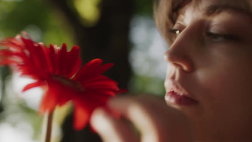 The woman picks at the red flower