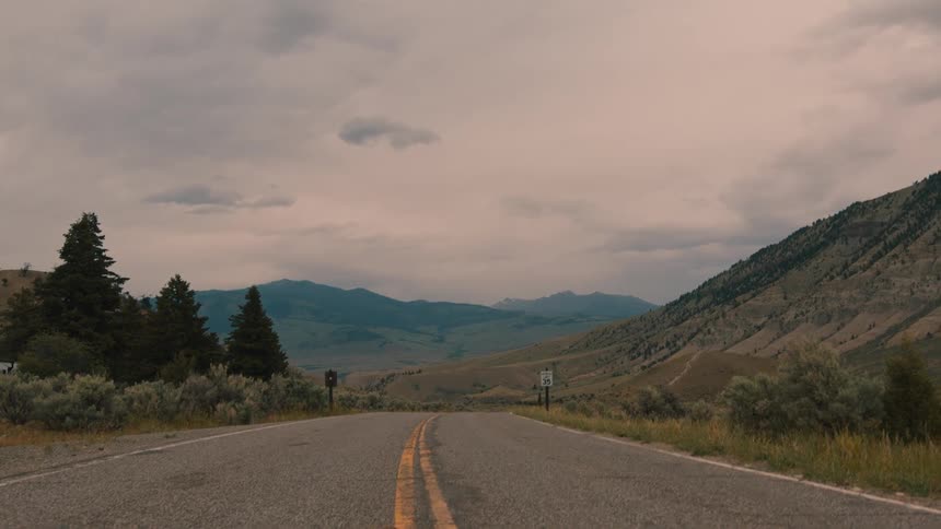 Asphalt road surrounded by mountains on a cloudy day