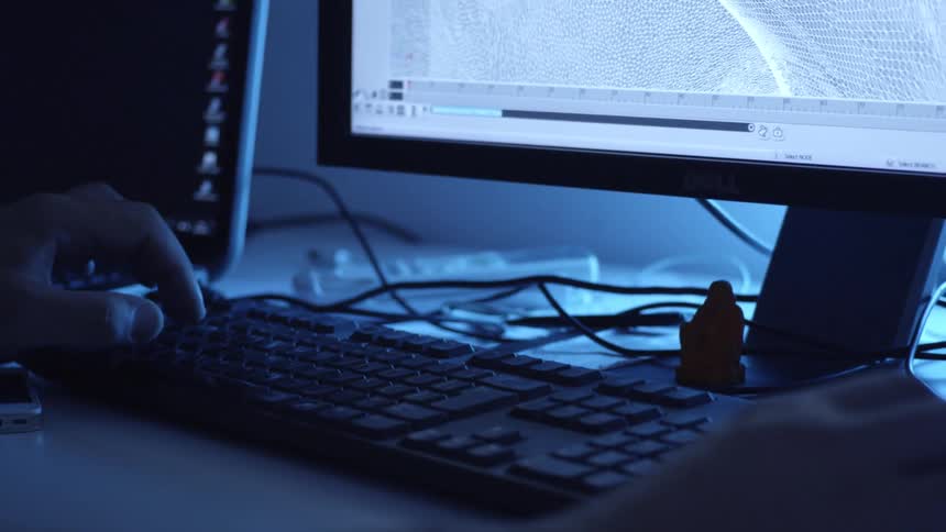 A hand is shown typing on a computer keyboard and editing a project on the screen