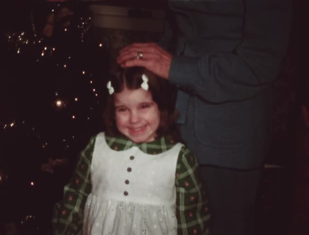A young girl smiles near a christmas tree