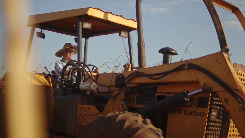 Farmer drives is tractor through the crops
