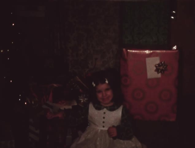 A girl smiles near some large presents