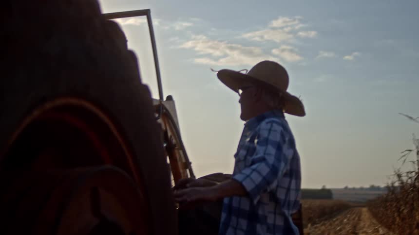 Male farmer inspects parts of a farm tractor on a farm during daytime