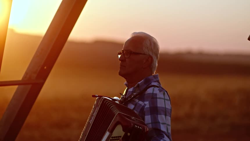 The man presses the accordion while playing on the farm