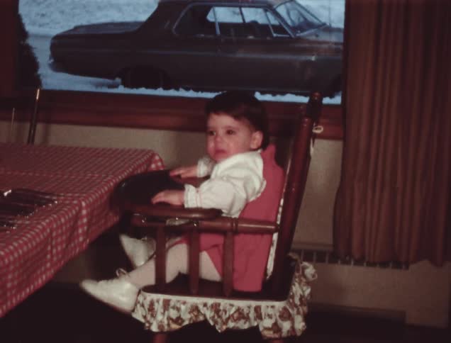 A child sits in a high chair at a table