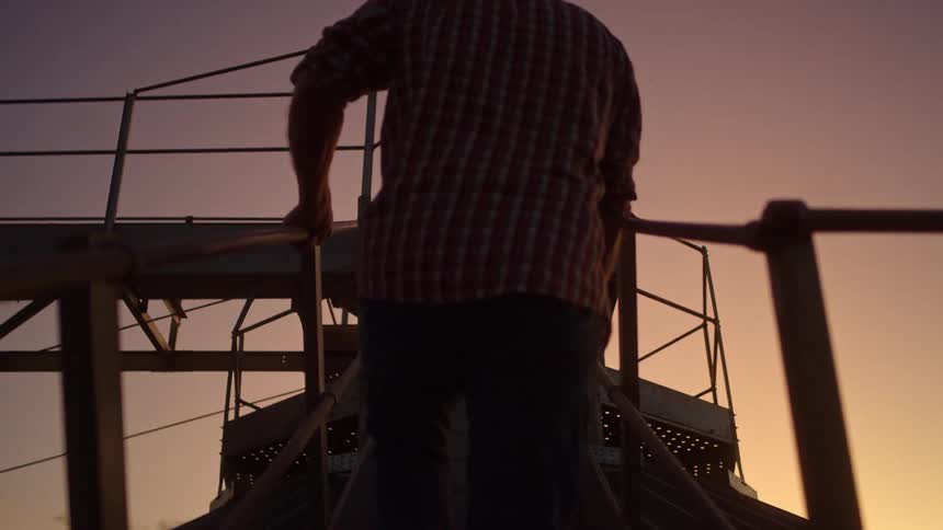 The man is climbing the metal stairs at sunrise