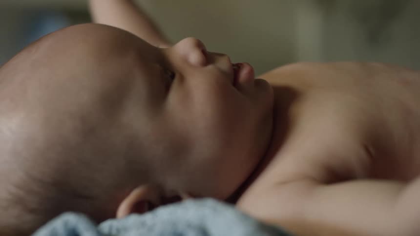 Close up of a baby raising their arms playfully while lying down