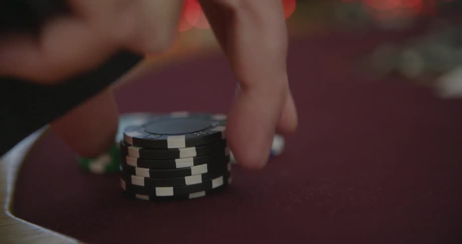 A man grabs poker chips and moves them into the center of the table