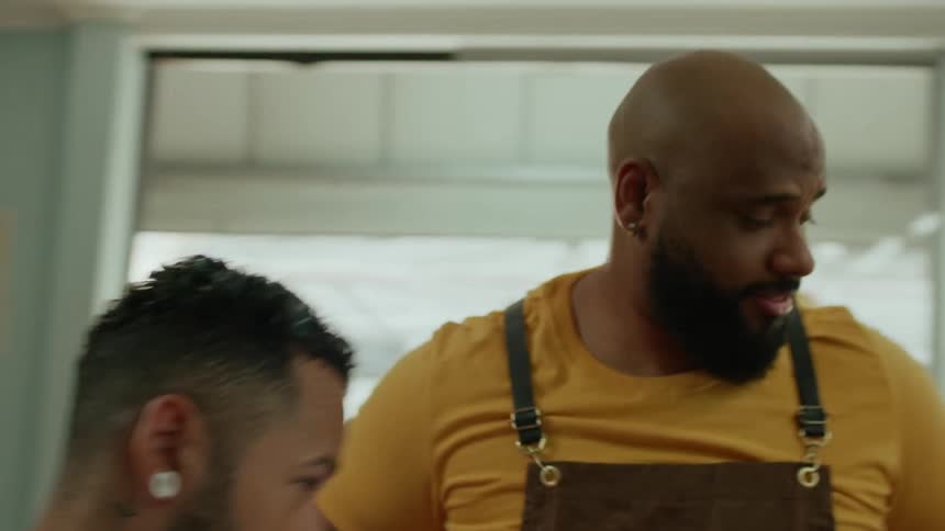 Barber puts cover cloth around a mans neck to start shaving at dawn while having conversation