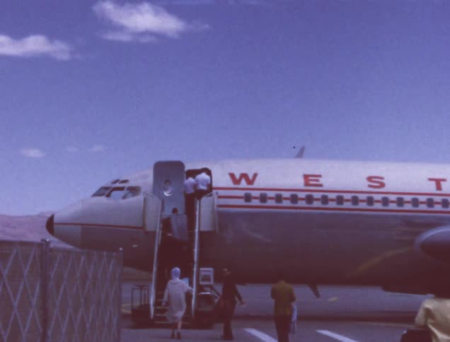 People walk along the runway towards an airplane