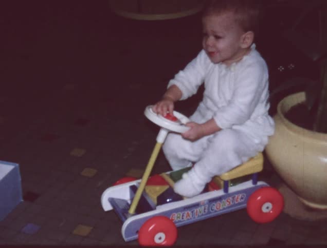 An older film of a baby playing on a toy in the front room