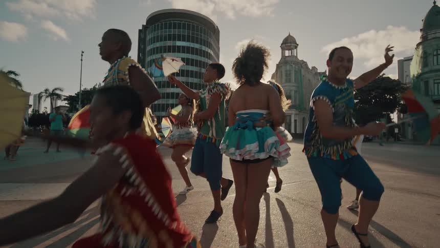 Group of dancers in traditional clothes dancing happily in a square in the city