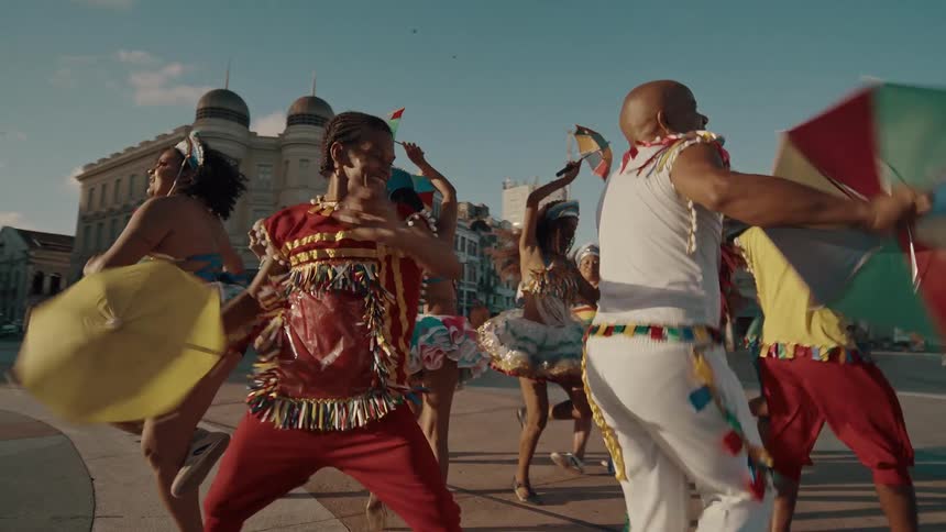 People in vibrant costumes joyfully dance and celebrate in a city street