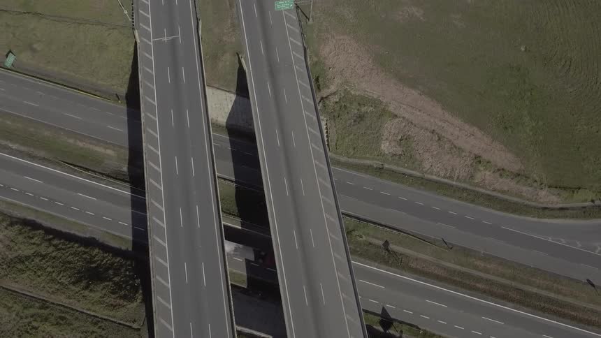 An aerial view shows vehicles traveling across a network of empty highways and intersecting roads