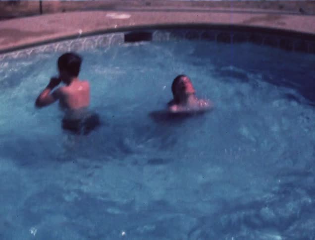 A child swimming and splashing in an in ground pool