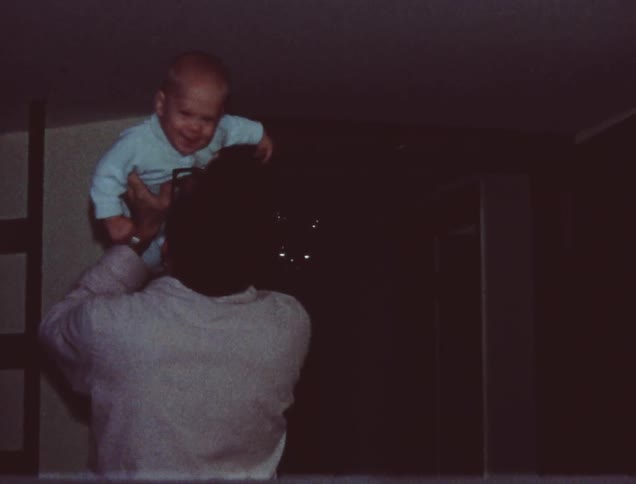 A man carries a baby into a room