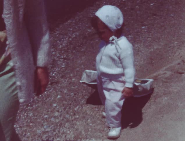 A small child drags a box along the beach