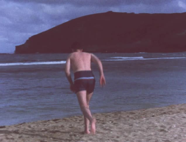 A man waves then runs into the water of a beach