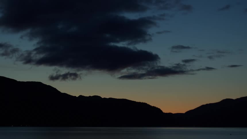 Dusk landscape with silhouetted mountains and calm lake