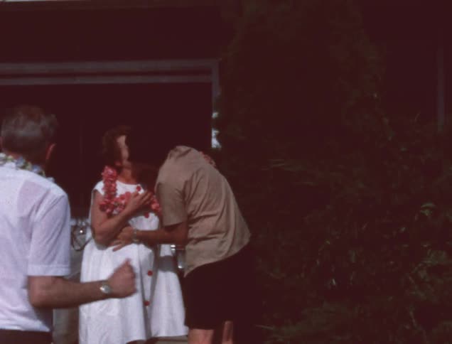 A man places a lei around the neck of a woman