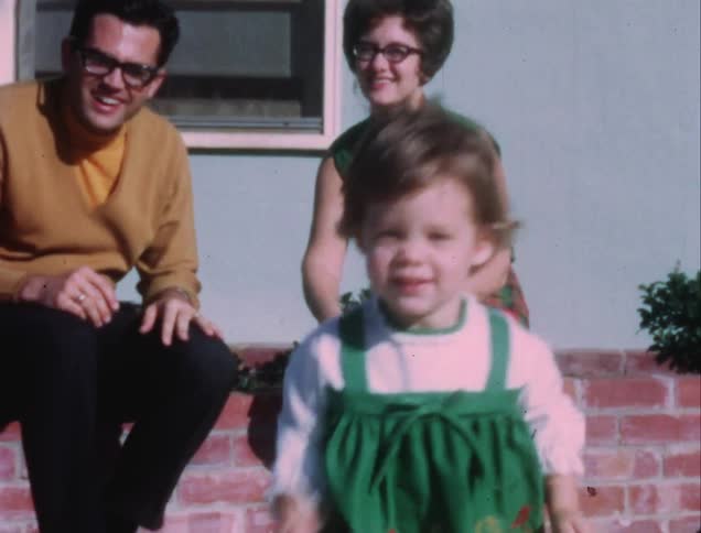 Toddler running in yard outside home while parents watch