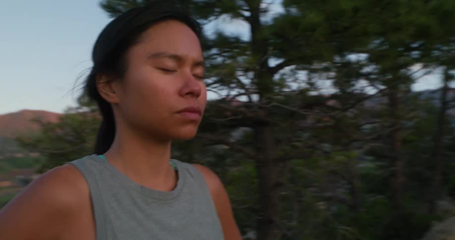 A young woman stands in the wild with her eyes closed meditating