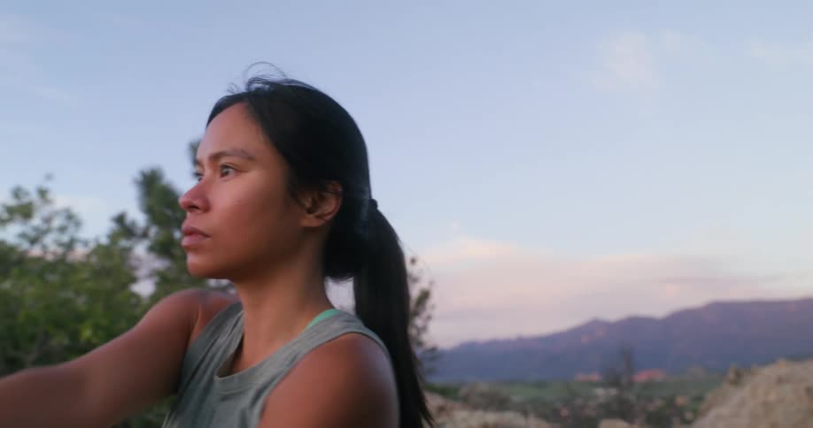 A young woman stretches on top of a mountain at midday