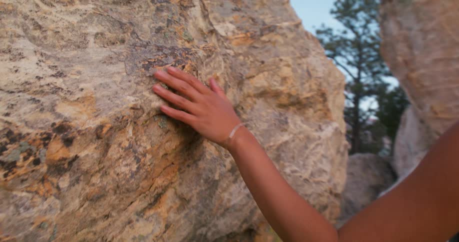 A woman traces her hand across the rocks