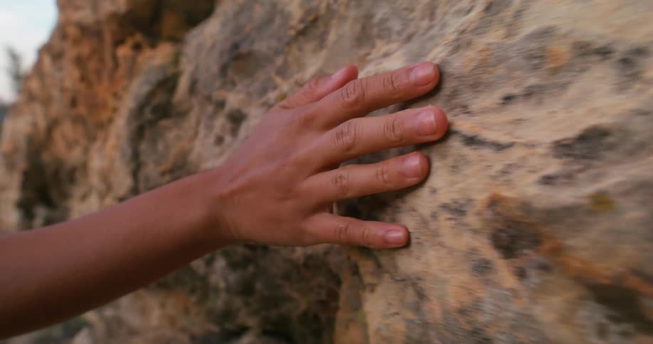Persons hand being passed on a rock wall