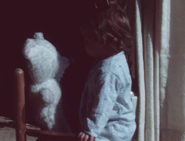 A young toddler plays with a stuffed bear