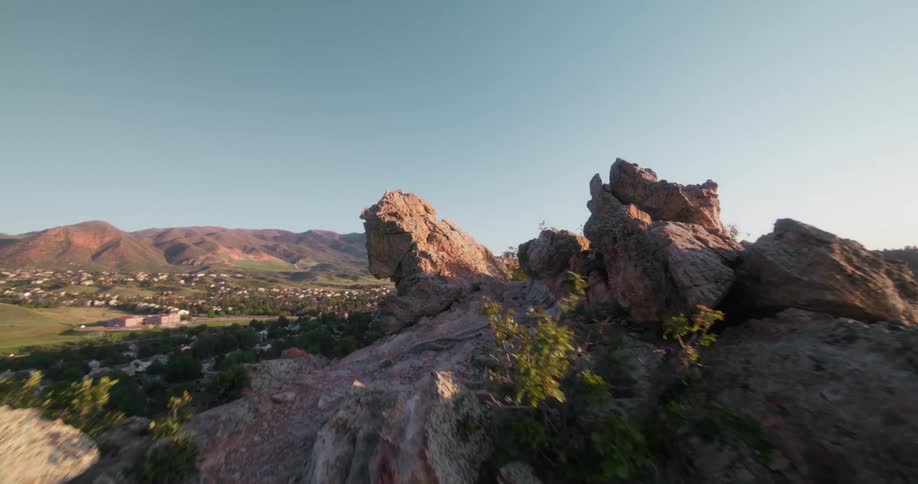 Large rocky formation sits under clear sky with distant mountains in the background