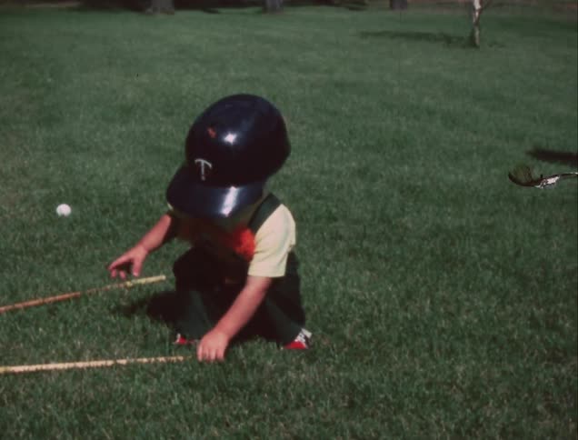 A young boy puts on a baseball helmet