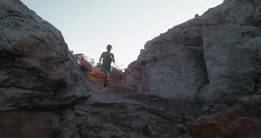 The woman is racing on the rocks of the mountain
