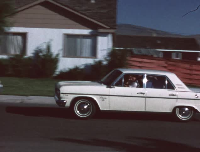 Man backing car out of driveway and waving as he drives off