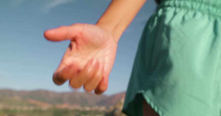 A persons hand revealing a subtle finger snapping motion the background suggests an outdoor possibly natural setting with blurred mountains and a clear sky