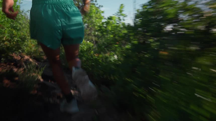 Woman in blue shorts running at high speed on a mountain trail