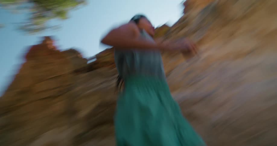 A young woman runs across rocky terrain at midday