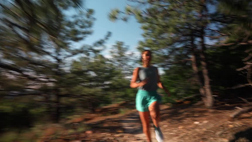 The woman is running fast past the trees