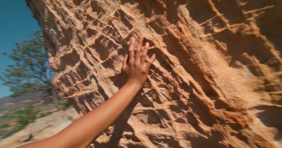 The woman is leaning on the large boulder