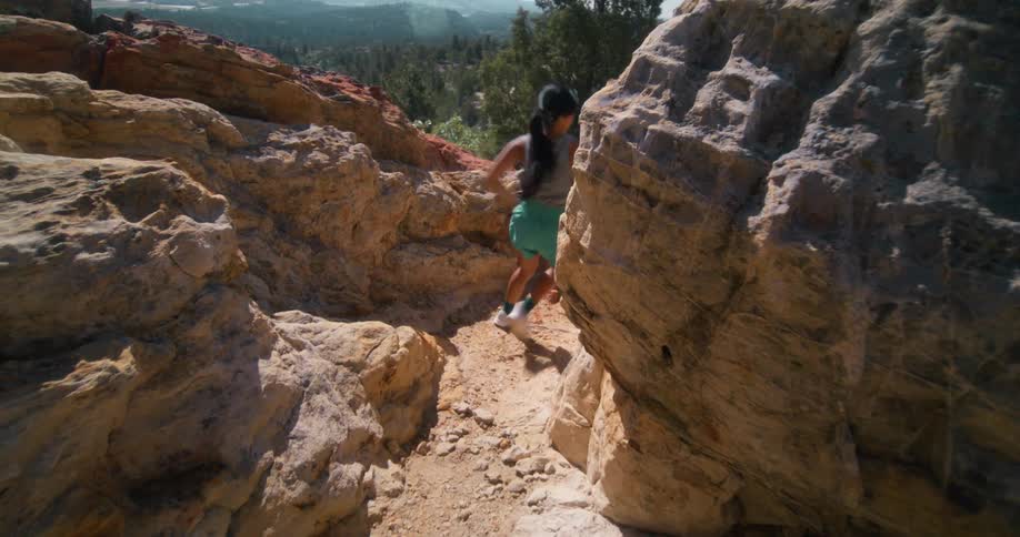 Woman is jogging through the valley of rocky terrain